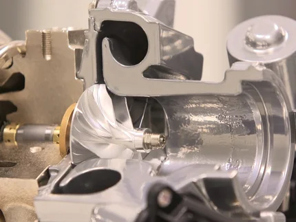 Nahaufnahme eines glänzenden Metallteils mit komplexer Form und mehreren Öffnungen.