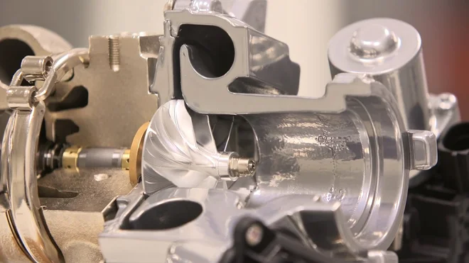 Nahaufnahme eines glänzenden Metallteils mit komplexer Form und mehreren Öffnungen.