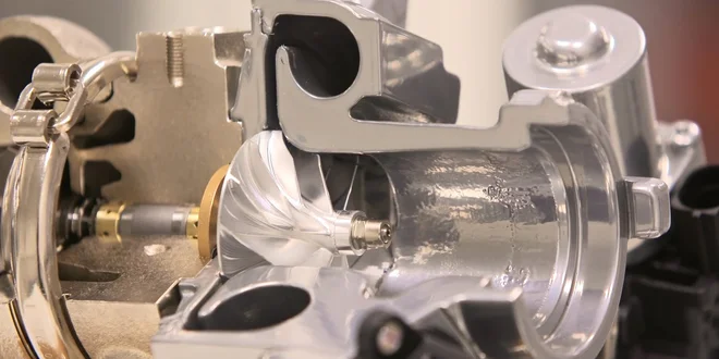 Nahaufnahme eines glänzenden Metallteils mit komplexer Form und mehreren Öffnungen.