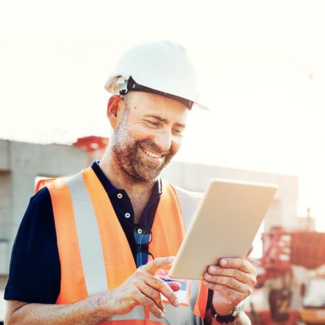 Ingenieur bearbeitet auf der Baustelle Rechnungen mit seinem Ipad.